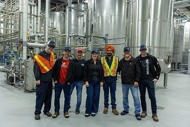 A group of people pose for photo at beer brewery.