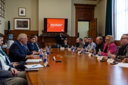 A large group sitting around a boardroom table.