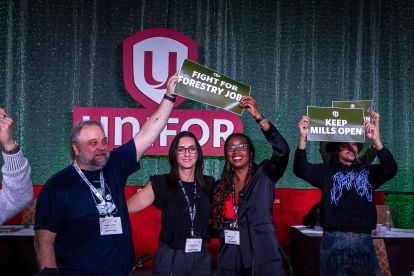 Four poeple on a stage holding up green &quot;Fight for Forestry Jobs&quot; signs