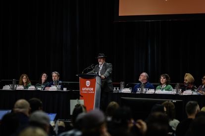 A group of people on stage sitting at a headtable with one standing at the podium