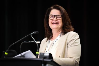 Carla Beck smiling at a podium