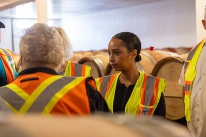 Close up of a women wearing a safety vest in a room full of wine barrels
