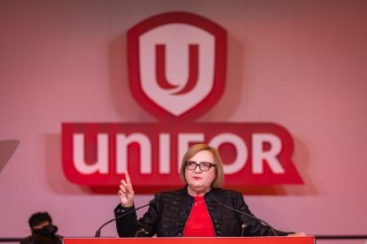 Lana Payne speaks at a mic in front of a Unifor sign