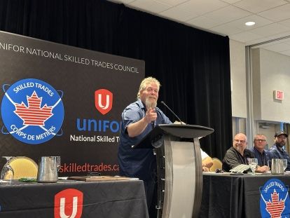 Man standing at a podium pointing out into the room.