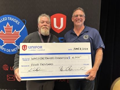 Two men hold up a large oversized cheque