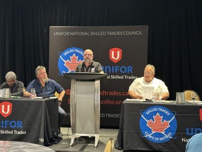 Man stands at a podium in front of a presentation screen