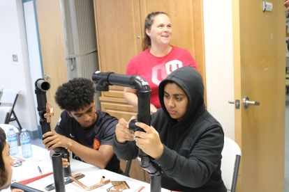 students working hands on a teacher in the background