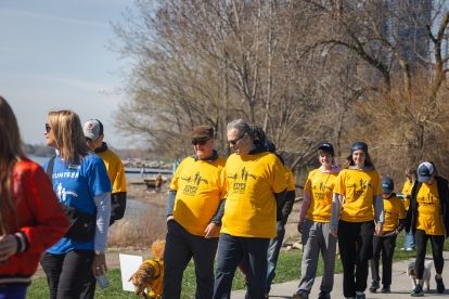 A group walking on a lakefront path wearing yellow steps for life shirts