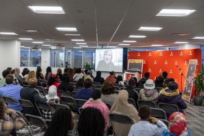 a room full a people sitting classroom looking at someone on a screen