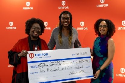 Three women hold up a giant cheque