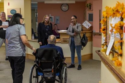 a resident in a wheelchair with staff and visitors