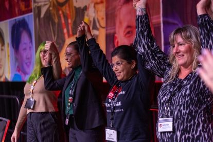 Four people stading arms locked and in the air.