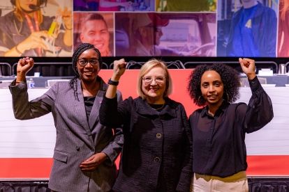 Three women holding up thie fists in solidarity