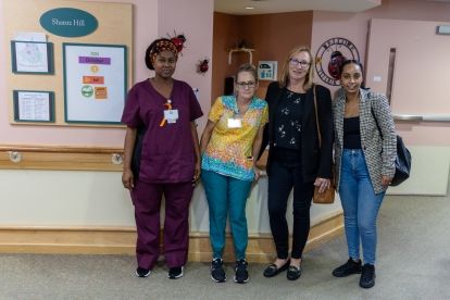 Four women standing in a hallway smiling