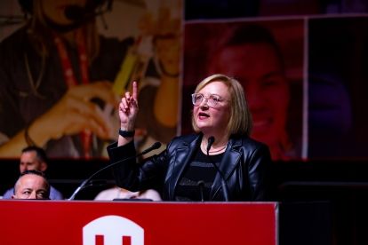 Lana Payne speaks at a podium with her are arm raised