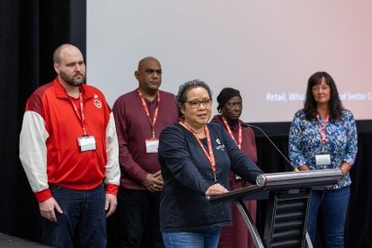 5 people at a podium with one woman speaking