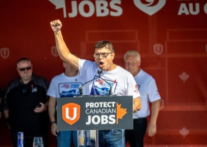 A man speaking at a podium arm raised making a fist.