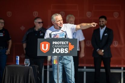 A man speaking at a podium pointing out