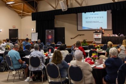 back room view of a conference looking at a presentation screen and women speaking