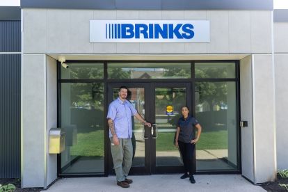 Two people standing in front of an entrance to Brinks