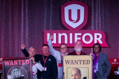 Five people on stage holding up wanted signs.