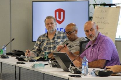 Three people sitting taking at a mic