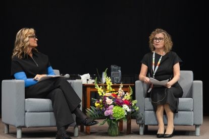 Two women sitting in chairs on a pannel