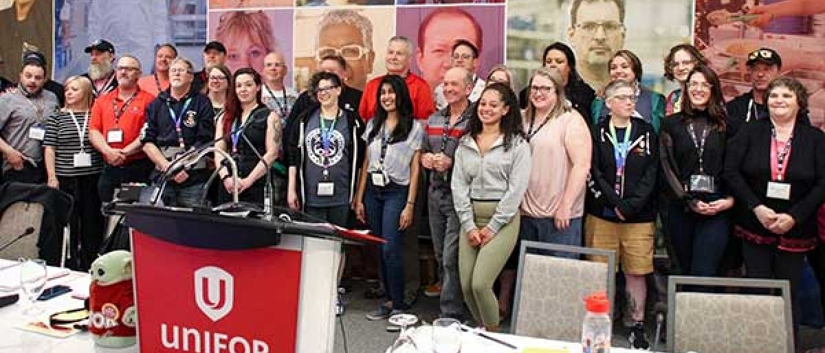 A large group of people gathered on stage behind a podium smiling.