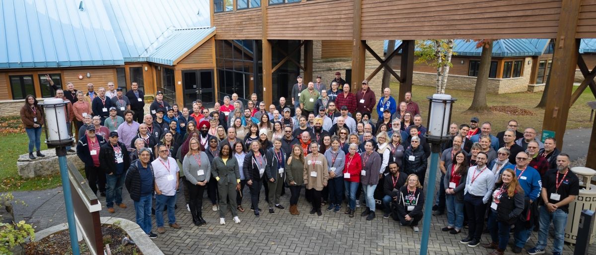 A large group outside of a building with a blue metal roof