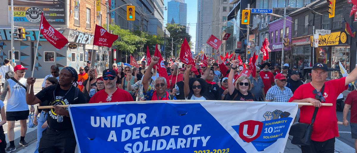 A group of people marching with a Unifor banner.