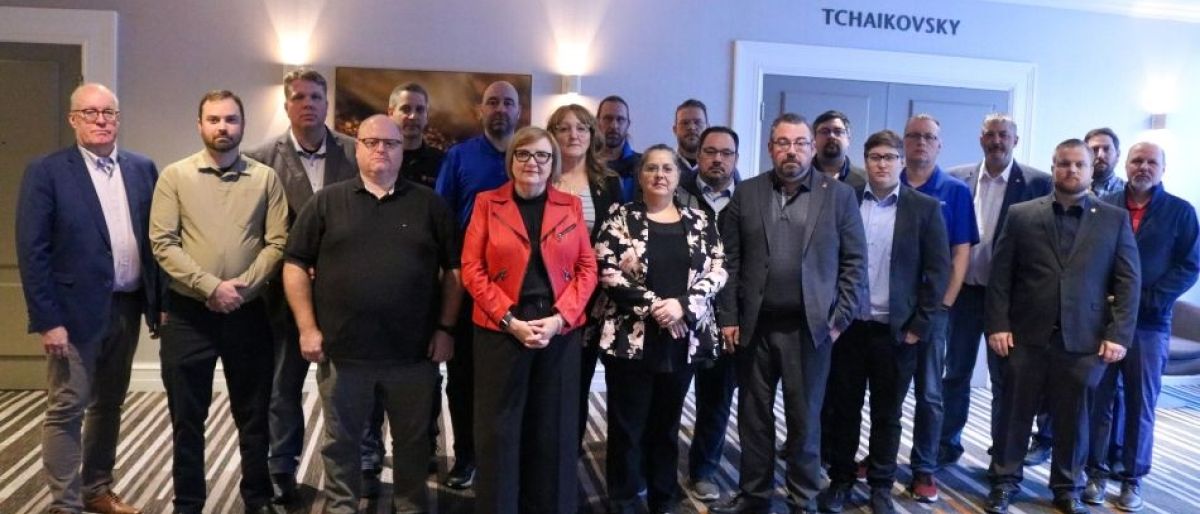 A large group standing in a hotel conference room
