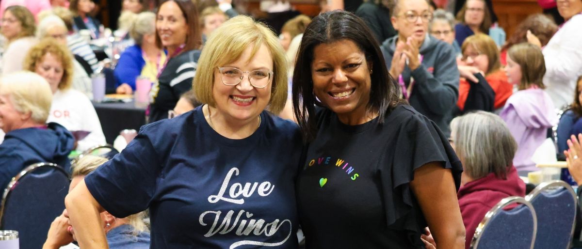 two women embracing with a crowd around them.