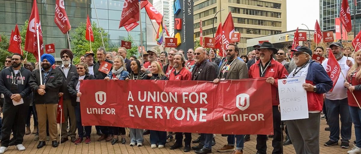 Group of Unifor leaders outside holding a banner that reads “A union for everyone” with other members in behind, some holding red Unifor flags