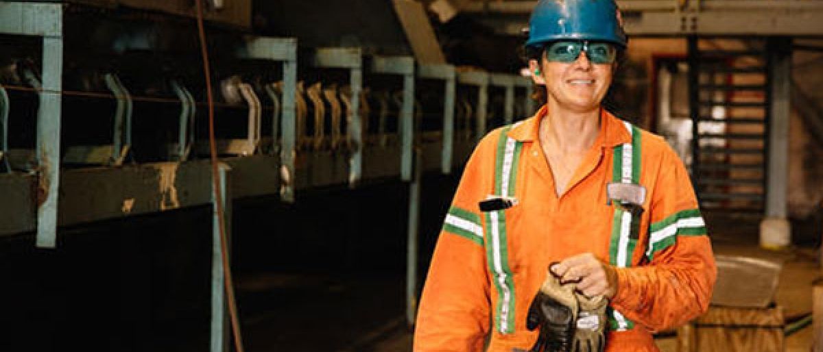 Trades women wearing a hard hat and orange overalls