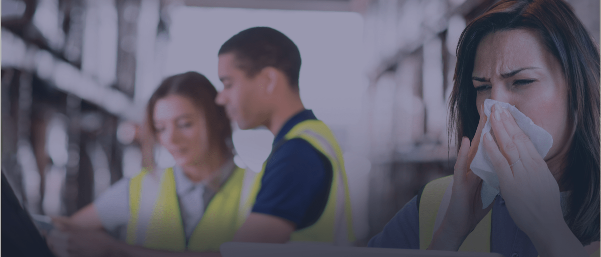 Workers wearing yellow safety vests one women appears sick blowing her nose into a napkin.