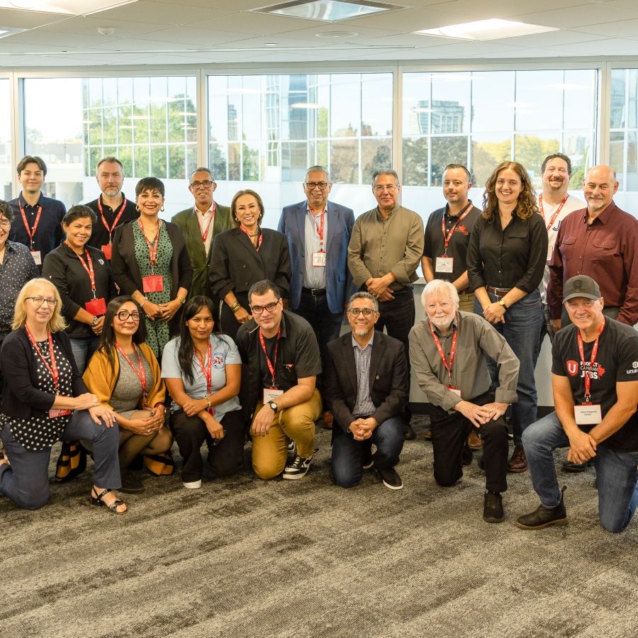 A large group posing in front of a window, a row in front kneeling, a row standing 