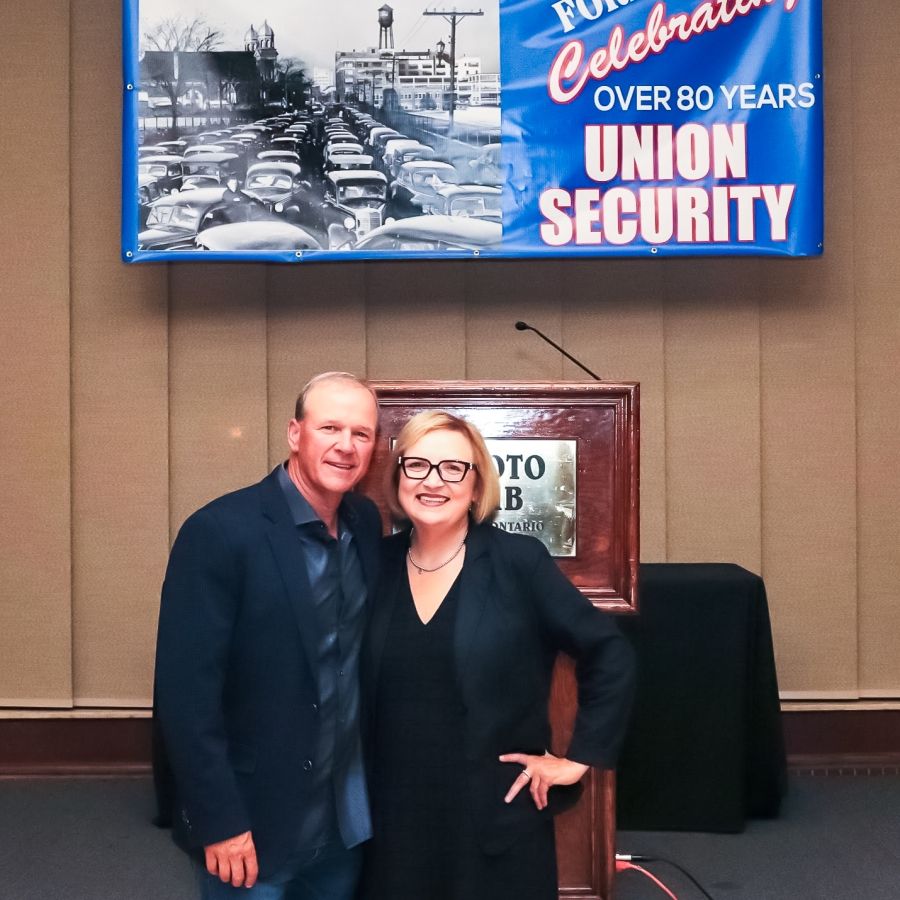 Two people standing front of the room with a sign overhead that reads, Local 200, Unifor. Rand formula, celebrating over 80 years, union security