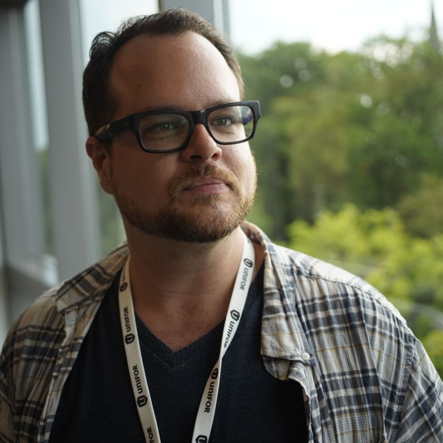 David Molenhuis stands in front of window overlooking forest.