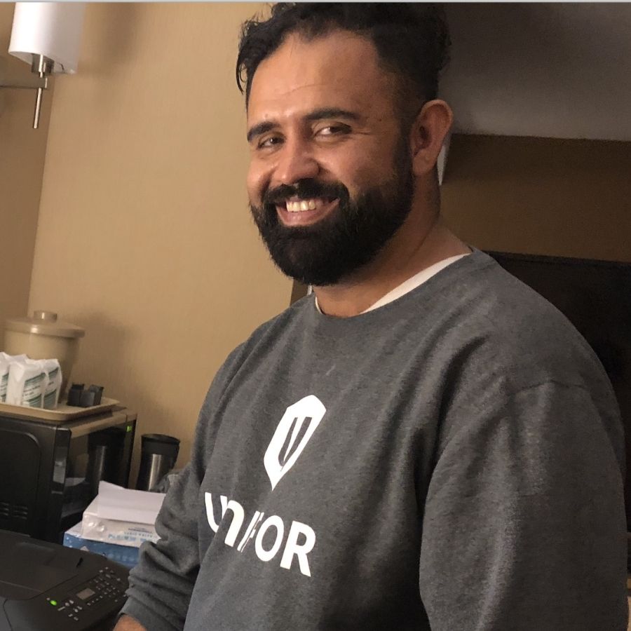 Hamid Osman stands in front of beige wall wearing Unifor shirt