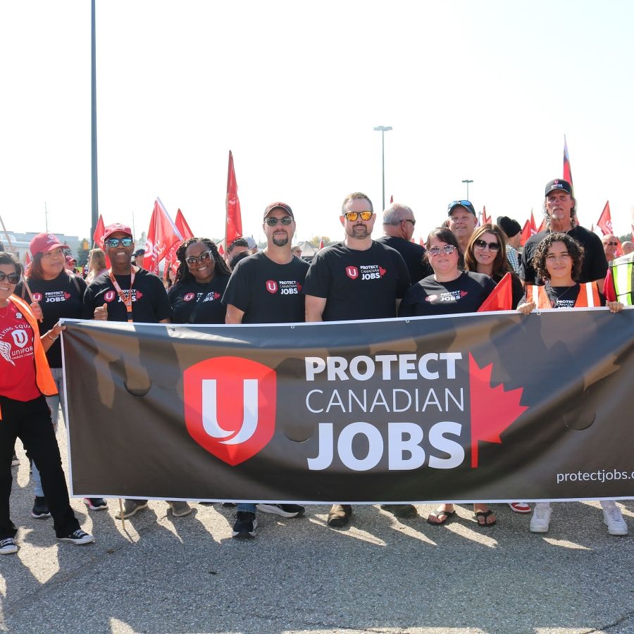 A group of people holding a ‘Protect Canadian Jobs’ banner 