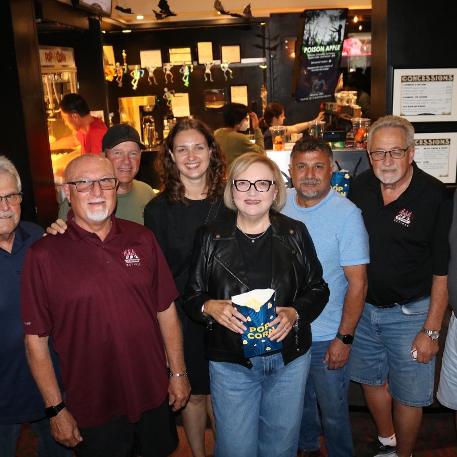 A group of people at a theatre a women in the middle holds a bag of popcorn