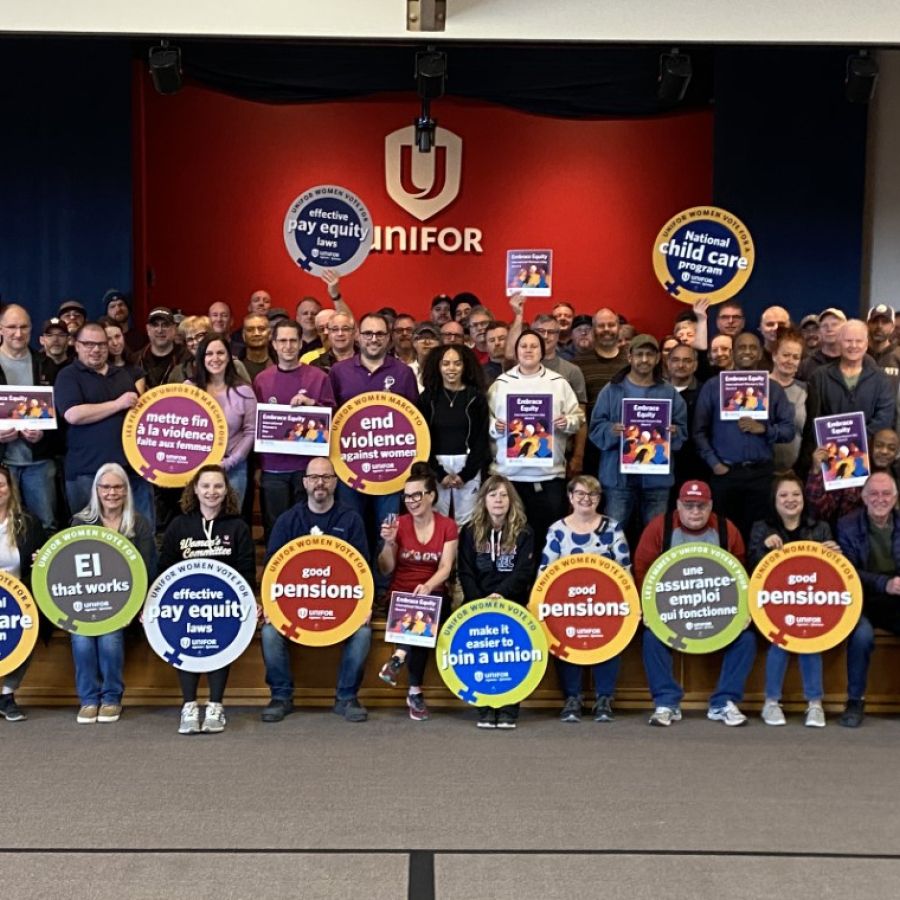 A large group of Unifor members holding signs with feminist slogans.