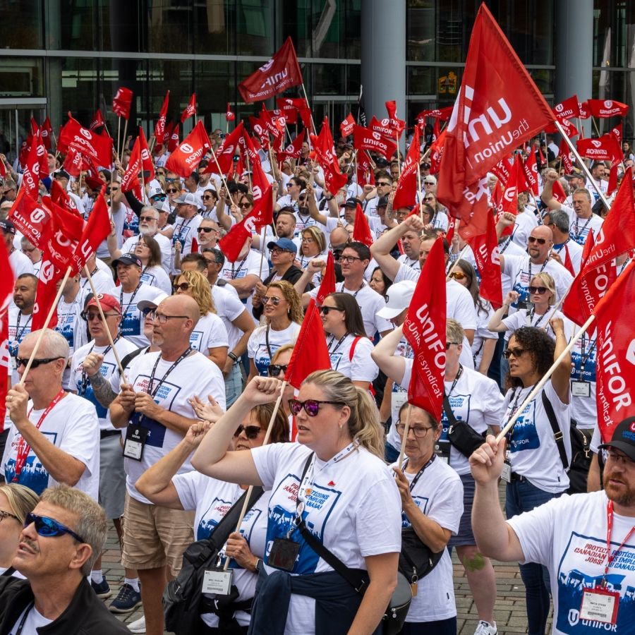 A sea of people holding red Unifor flags